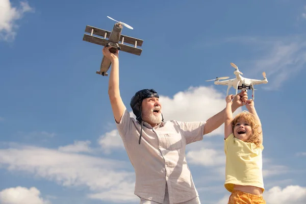 祖父と息子はおもちゃの飛行機と空に対するクワッドコプターのドローンで遊んでいます。飛行機旅行の夢を持つ子供パイロット航空機. — ストック写真