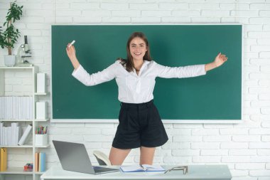 Kız öğrenci, lisede ya da üniversitede tebeşirle tebeşirle elini kaldırmış, heyecanlı amazet öğrencisini karatahta üzerine oturtmuş..