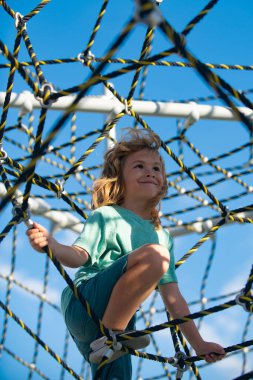 Sevimli çocuk gülümsüyor, oyun alanında oynarken mutlu..