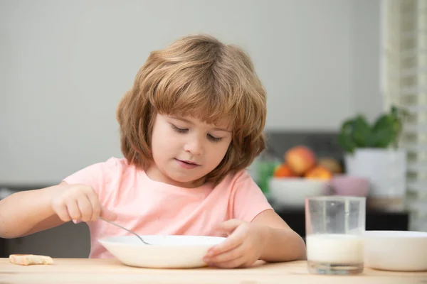Portrait of cute child eating soup meal or breakfast having lunch by the table at home with spoon. Kids healthy food. — Stock Photo, Image