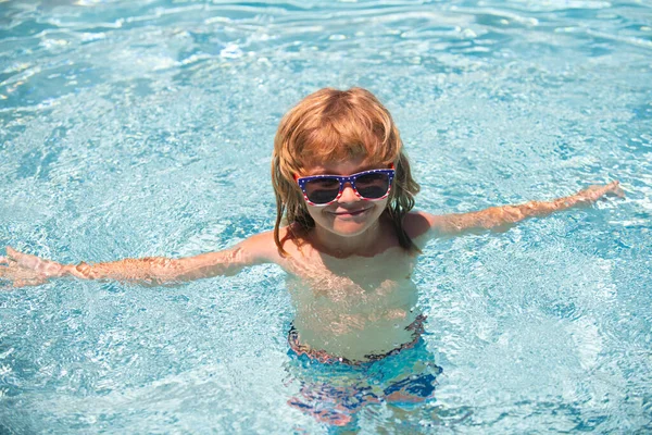 Dziecko w letnim basenie. Słodki chłopiec w wodzie bawi się wodą. Uśmiechnięty mały chłopiec w okularach przeciwsłonecznych w słoneczny dzień. — Zdjęcie stockowe