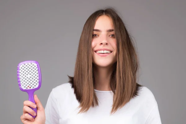 Vrouw maakt kapsel met kam. Mooie jonge vrouw met gezond en glanzend haar, studio. Close-up op jonge vrouw kammen haar. — Stockfoto