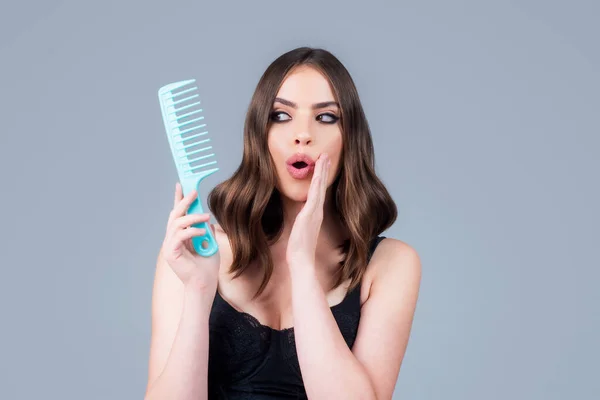 Surprised woman hairdresser with comb brushing hair. — Stock Photo, Image