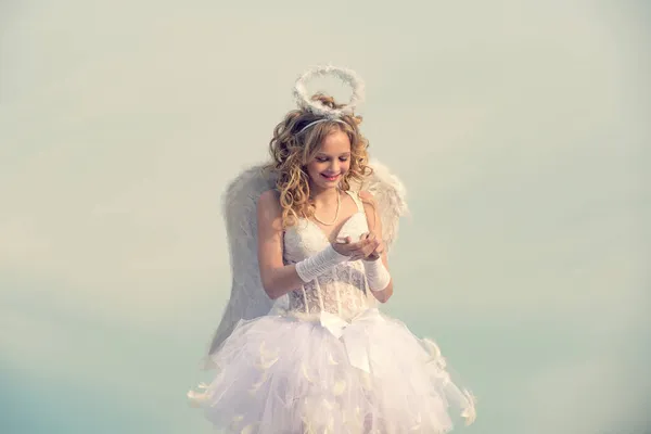 Αγγελική κοπέλα με σγουρά ξανθά μαλλιά. Εορταστική κάρτα χαιρετισμού τέχνης. Βέλος αγάπης. Όμορφο σγουρό κοριτσάκι με λευκό φόρεμα και φτερά - Angel cupid girl. — Φωτογραφία Αρχείου