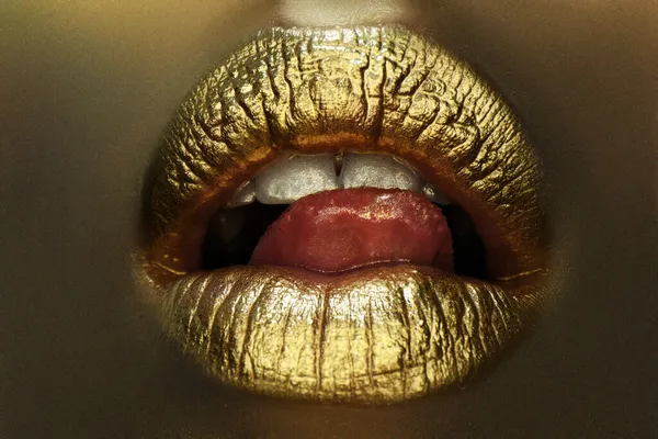 Sexy tong. Sensuele lik. Gouden lippen, gouden lipgloss op sexy lippen, metalen mond. Schoonheid vrouw make-up close up. — Stockfoto