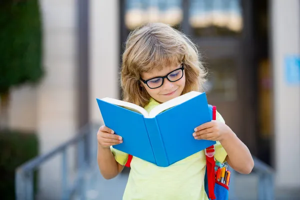 Petit étudiant souriant portant un sac à dos d'école et tenant un cahier d'exercices. Portrait d'élève heureux en dehors de l'école primaire. Gros plan de souriant écolier hispanique regardant la caméra. — Photo