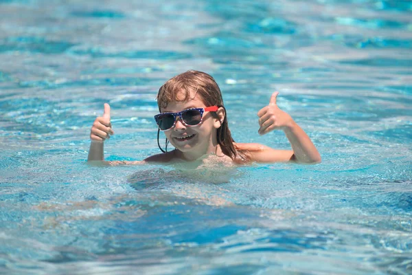 Niño con pulgares arriba en gafas de sol relajarse en la piscina de verano. Niños activos estilo de vida saludable, actividad deportiva acuática y clases de natación en vacaciones de verano con niños. —  Fotos de Stock