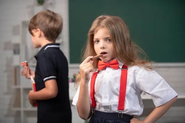 Portret van een aantrekkelijk vrolijk meisje dat gezond voedsel eet of chocoladesnoep eet in de klas op de basisschool. — Stockfoto