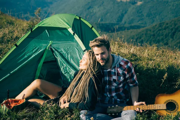 Pareja romántica enamorada de acampar al aire libre y sentada cerca de la tienda. Feliz hombre y mujer en unas vacaciones de camping románticas. — Foto de Stock