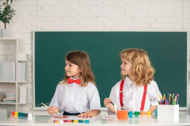 Çocukların yaratıcı eğitimi. Okullu çocuklar sınıfta kurşun kalemle renkli resimler çiziyorlar. Sanat ve zanaat dersinden zevk alan sevimli öğrencilerin portresi..