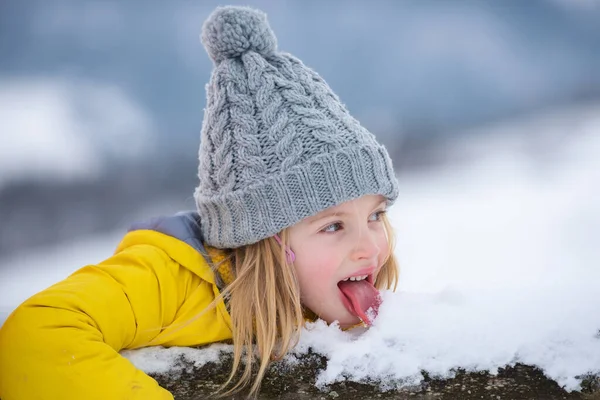 Lustig liten flicka som går och äter snö på vinterdagen. Spännande jul semester. Koncept för förkylning och influensa. Tunga med snö. — Stockfoto