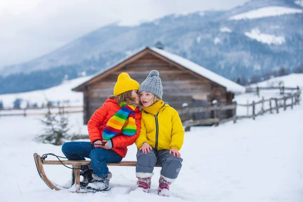Embrasse. Drôle de garçon et de fille s'amuser avec un traîneau en hiver. Des enfants mignons jouant dans la neige. Activités hivernales pour les enfants. — Photo