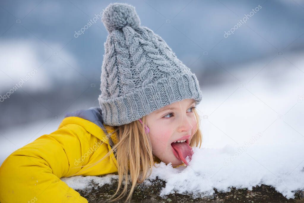 Funny little girl walking eating snow on winter day. Excited christmas holiday. Kids cold and flu concept. Tongue with snow.