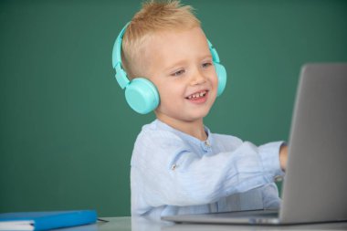 Kulaklıklı gülümseyen çocuk öğrenci internetten ders çalışıyor, kulaklıklı çocuk internet dersi alıyor. Eğitim, okul, teknoloji ve çocuk kavramı.