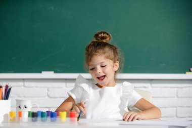 Okulda resim çizen şirin küçük bir anaokulu çocuğu. İlkokulda çocuk resimleri. Okulda resim çizen tatlı bir kız..