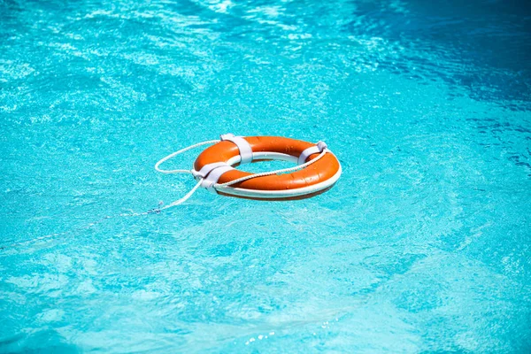 Cinturón salvavidas en el mar o la piscina. Anillo inflable naranja flotando en agua azul. Boya salvavidas para protección y seguridad de ahogamiento. — Foto de Stock
