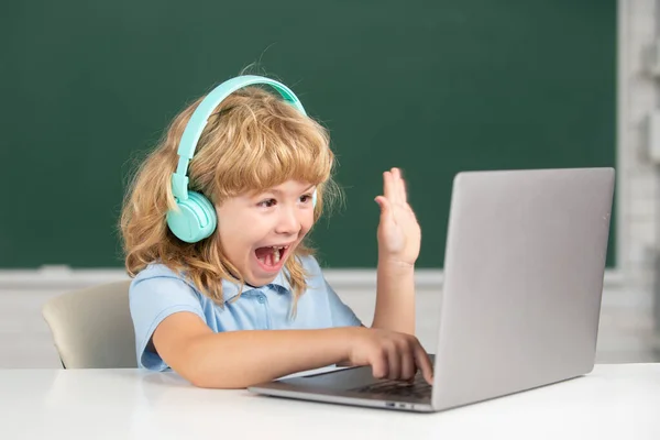 Opgewonden schooljongen, verbaasd leerling draagt koptelefoon schrijven op laptop, luisteren audio les gebruik computer. Videocall, e-studie met docent op afstand. — Stockfoto