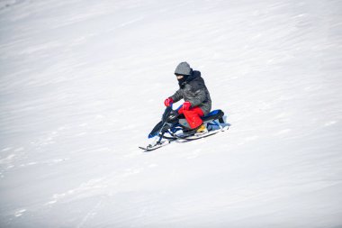 Doğada kış yürüyüşünde oynayan mutlu çocuk. Kızak sürmekten hoşlanan, karda kızak kayan bir çocuk..