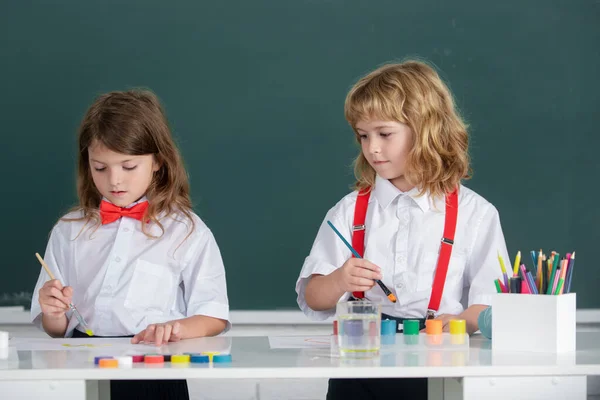 Linda escuela amigos niños dibujo y pintura en la escuela. Amistoso chico una chica divertida pupilas dibujar en el fondo de pizarra. Amistad en la escuela. — Foto de Stock