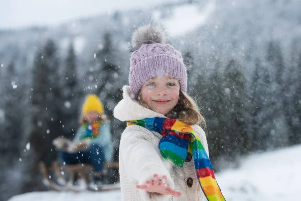 冬の屋外で雪の中で面白い興奮した子供の女の子の顔。霜雪の日の冬の屋外の子供たち。冬の背景を持つ公園で素晴らしい子供の雪合戦。表現力豊かな子供の感情. — ストック写真