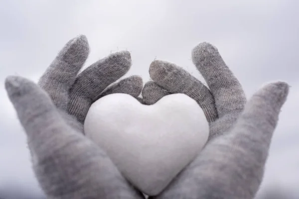 Ręce w rękawiczki z dzianiny z sercem ze śniegu. Kocham zimę. Walentynki tle. — Zdjęcie stockowe