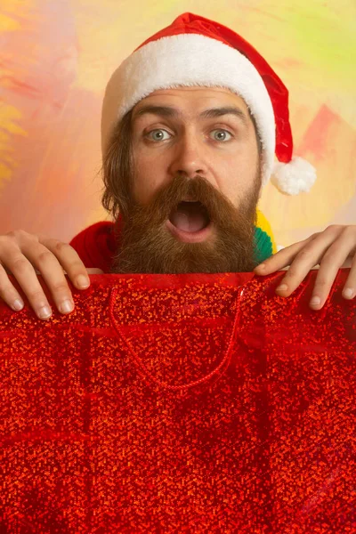 Alışveriş çantalı, heyecanlı Noel adamı. Noel alışverişi. Noel Baba hediyeler alıyor, adam sezonluk satışlardan ve indirimlerden hoşlanıyor, kırmızı arka plan.. — Stok fotoğraf