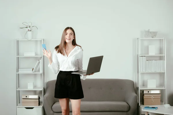 Jonge zakenvrouw met laptop en creditcard op kantoor. Secretaris vrouw in formele kleding werkt aan project op modern kantoor. — Stockfoto