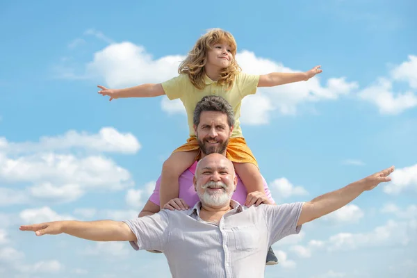 Голод поколений. Отец, сын и дедушка счастливый мульти genration семьи с поднятием рук или с распростертыми объятиями летать по небу. — стоковое фото