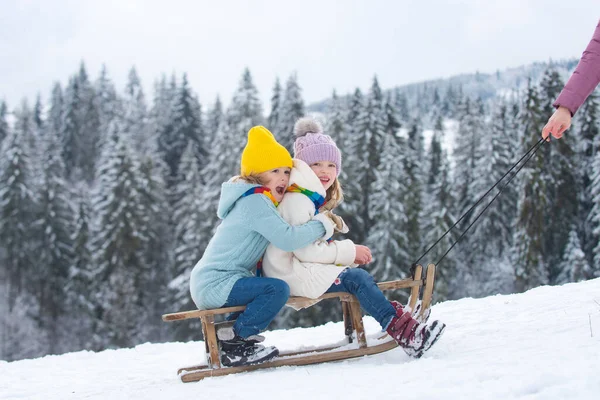 Happy little boy and girl sledding in winter. Kids sibling riding on snow slides in winter. Son and daughter enjoy a sleigh ride. Family christmas holiday outdoor. — Stock Photo, Image