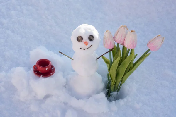 Sneeuwman met kopje koffie en lente bloemen tulpen. Snowman op de achtergrond van sneeuwvlokken textuur. Achtergrond voor Kerstmis ontwerp. — Stockfoto