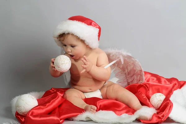 Aniołek na Boże Narodzenie. Piękne maleństwo świętuje święta. Noworoczne wakacje. Dziecko w kapeluszu Mikołaja z prezentem. Mikołaj dziecko. — Zdjęcie stockowe