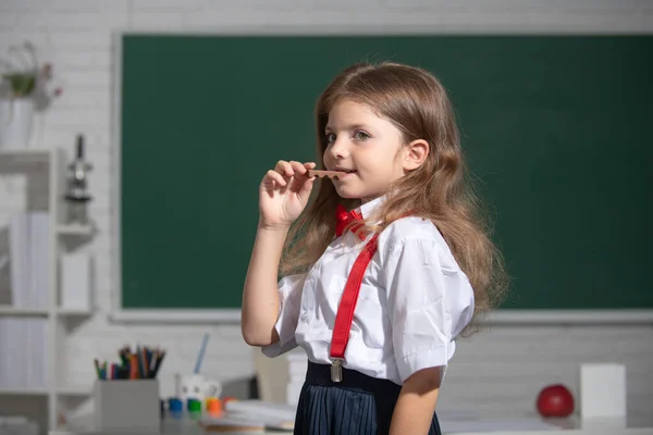 Sınıfta çikolata yiyen, güzel, okul üniformalı bir kızın portresi. İlkokul ve ilköğretim. — Stok fotoğraf