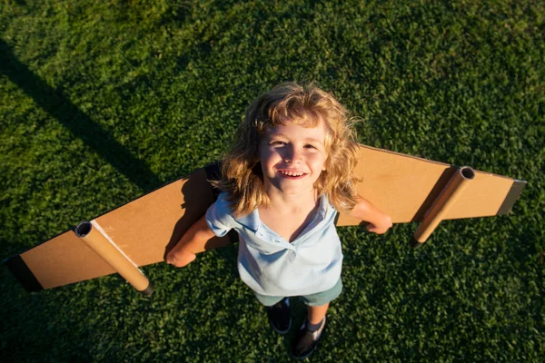 Top view barn resenär med ryggsäck vingar. Barnlek pilot flygare och drömmar utomhus i parken. — Stockfoto