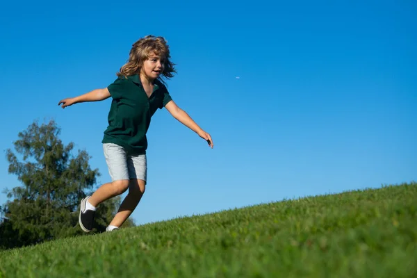 잔디 위를 뛰어다니는 기분좋은 소년. 밝은 봄 들판에서 하늘을 배경으로 노는 행복 한아이. 자유롭고, 활동적 인 아이들 이 야외에서. 즐거운 활동. — 스톡 사진