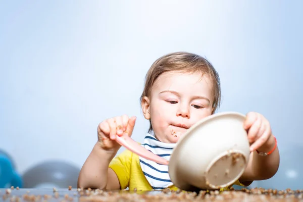 Bebek yemek yiyor. Tabağı ve kaşığı olan komik çocuk.. — Stok fotoğraf