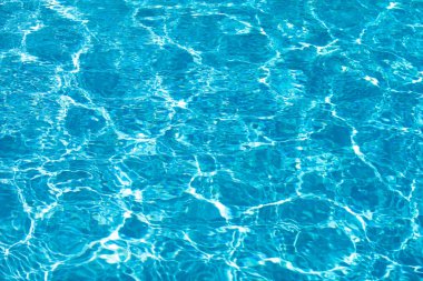 Yüzme havuzundaki mavi suyun arka planında güneş yansıması, havuzda dalgalı su dalgaları. Temiz su arkaplanı.
