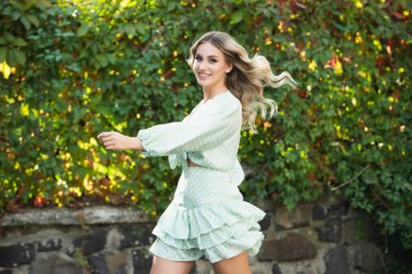 Havalı bahar kıyafetleri içinde güzel, heyecanlı, gülen bir kadın. Kadın stili model şehir caddesinde yürüyor. Bahar trendi, moda kıyafeti.