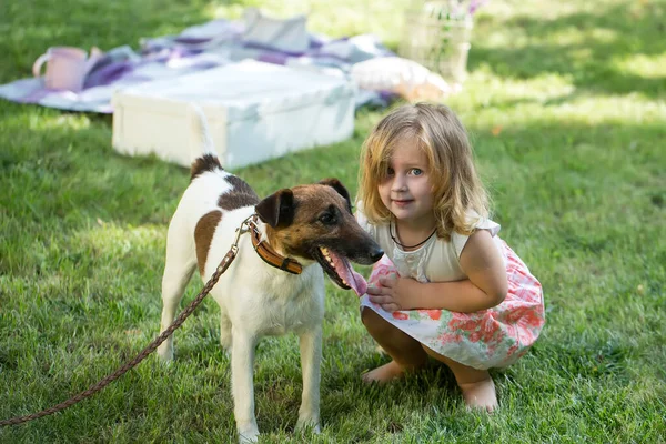 Little baby playing girl with Russell Terrier dog in nature on the green grass. Kids playing. Baby and summer sunny weather. — Stock Photo, Image