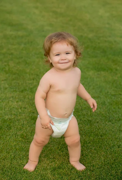 Kind, grappige baby in luier spelen op groen gras veld, zomer outdoor kids levensstijl. — Stockfoto
