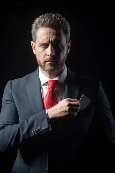 Retrato de un elegante hombre de negocios apuesto aislado en negro. Guapo hombre de negocios de mediana edad con tarjeta de crédito en traje posando sobre un fondo negro con espacio para copiar. — Foto de Stock