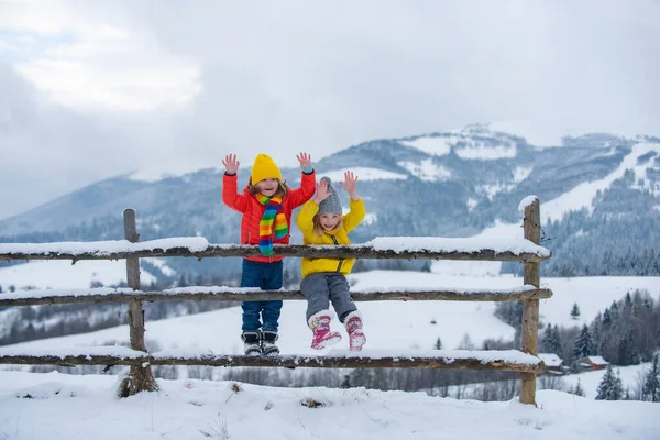 Ενθουσιασμένο κοριτσάκι και αγόρι να απολαμβάνουν το χειμώνα. Τα παιδιά παίζουν έξω στο χιόνι. Εξωτερική διασκέδαση για οικογενειακές διακοπές Χριστουγέννων. — Φωτογραφία Αρχείου