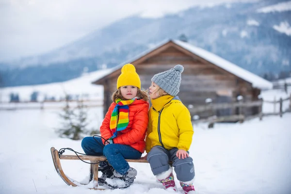 Děti sáňkaří, jezdí na saních. Děti syn a dcera si v zimě hrají ve sněhu. Venkovní děti zábava pro vánoční rodinnou dovolenou. Vánoční krajina. — Stock fotografie