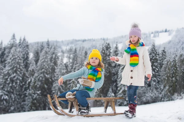 Bambini ragazzo e bambina godendo di un giro in slitta. Bambini che insieme fanno slittino, giocano all'aria aperta sulla neve in montagna in inverno. Bambini fratello e sorella in vacanza di Natale. Divertimento bambini invernali. — Foto Stock