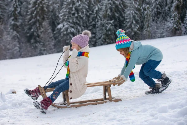 Bonito menino e menina crianças brincando em um passeio de inverno na natureza. Inverno tricotado crianças roupas. Tempo frio. Miúdos felizes com chapéu de malha, cachecol e camisola. Montanhas frias e nevadas de inverno. — Fotografia de Stock