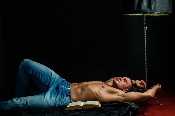 Gespierd slapen sexy man, liggend in bed op zwarte achtergrond, naakt romp. — Stockfoto