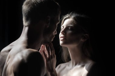 Birbirine aşık romantik bir çift siyah arka planda sarılıp öpüşüyor. Şehvetli çift öpücüğü. Ben de seni seviyorum. Romantik ve aşk.