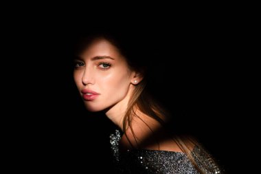 Stüdyoda poz veren genç bir kadın. Işık ve gölge. Yüzünde koyu renk ışık olan güzel bir kadının moda portresi. Kızların yüzü gölgeli, çekici kadın model..