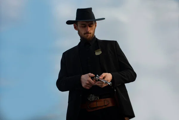 Homem cowboy americano. Bonito tipo ocidental brutal. Xerife com armas ocidentais selvagens, revólver de pistola vintage e munições do xerife. western americano. Oeste selvagem com cowboy. — Fotografia de Stock