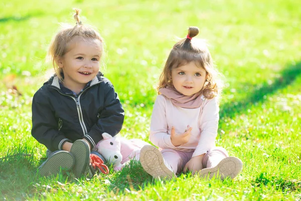 Baby auf dem grünen Rasen im Sommerpark. Bruder und Schwester spielen gemeinsam auf einer grünen Wiese. Glückliche Kinder spielen auf grünem Gras im Frühlingspark. — Stockfoto