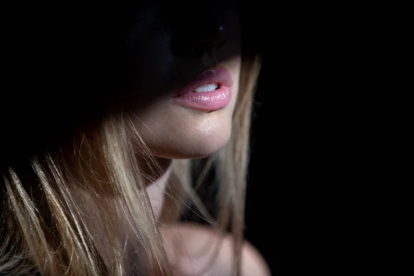 Junge Frau posiert im Studio vor schwarzem Hintergrund. Licht und Schatten auf den Lippen. Modeporträt einer schönen Frau mit dunklem Licht im Gesicht. — Stockfoto